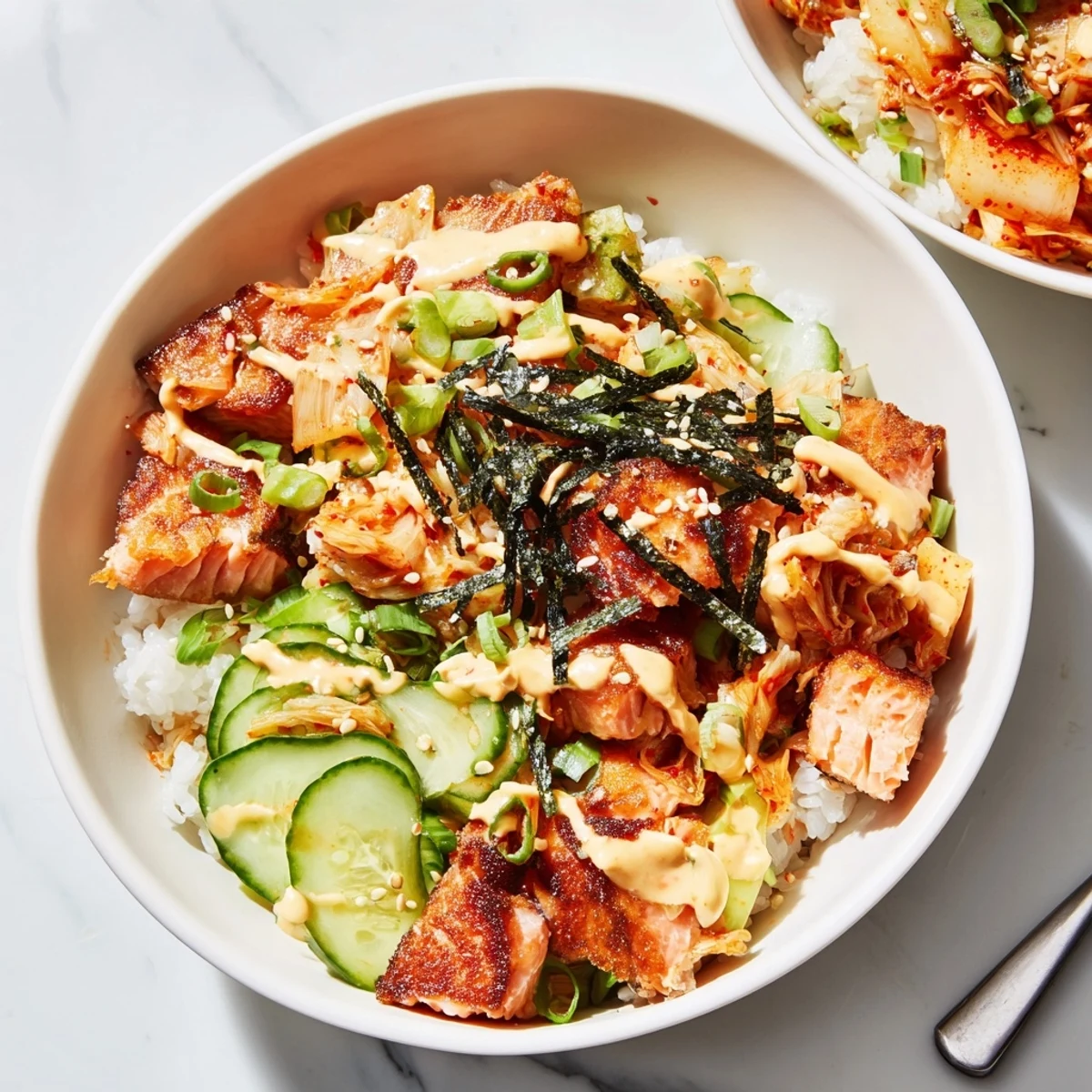 Enjoy a crispy salmon rice bowl garnished with tangy kimchi and avocado slices.  