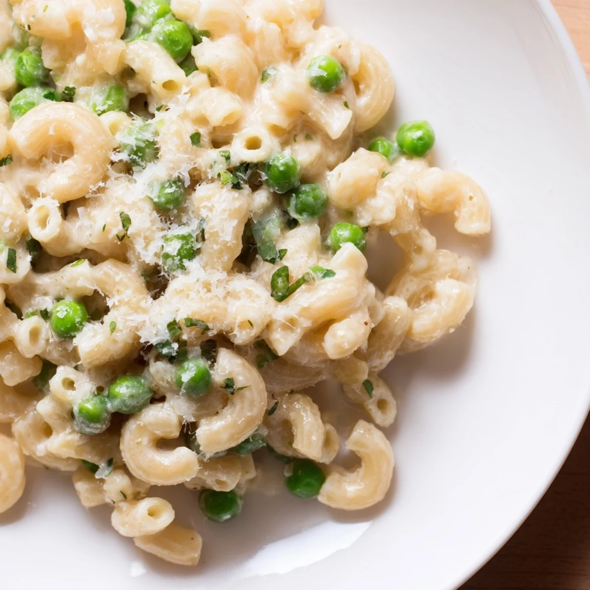 Grated cheese sprinkled over a plate of delicious, homemade Macaroni & Peas with creamy sauce.
