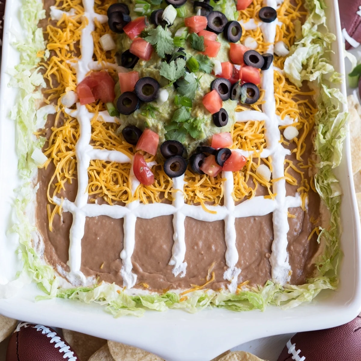 Savory Football Field Dip: A festive layered dip speckled with olives and tomatoes perfect for parties.