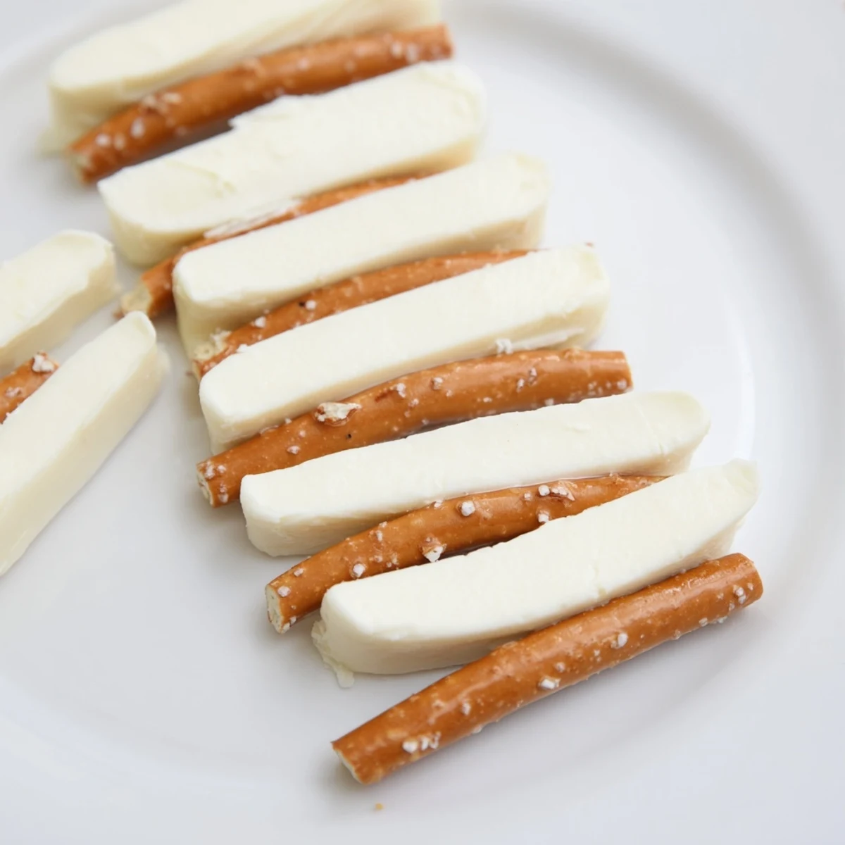 Delicious string cheese and pretzel rods served on a platter, ideal for a light, vegetarian snack.