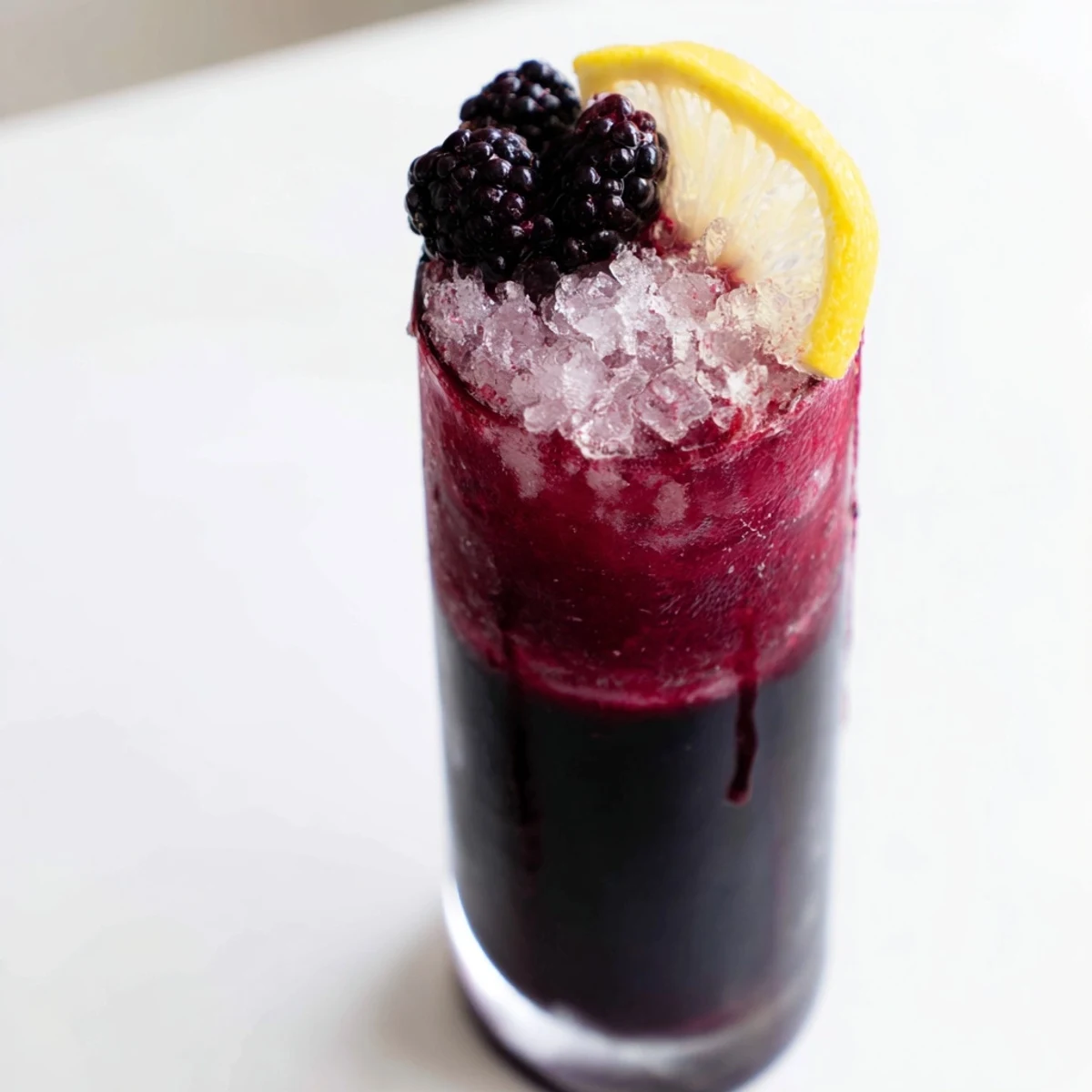 Dark Matter Mocktail, layered black drink garnished with blackberries, offers a refreshing, non-alcoholic treat.