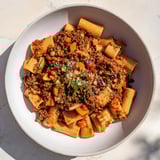 Cozy, comforting High-Fiber Lentil Bolognese, bubbling, with vibrant red crushed tomatoes and lentils.