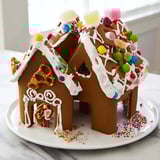 Brightly decorated gingerbread house kit, ready to be built with included royal icing and candies.