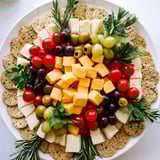 Festive Jingle Bell Cheese & Cracker Wreath with creamy cheeses, juicy grapes, and fragrant rosemary sprigs.