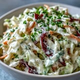 Freshly tossed Coleslaw With Creamy Dressing with crunchy cabbage, carrots, and herbs in a white bowl.