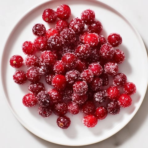 Vibrant, glistening vegan candied cranberry garnish piled high, perfect topping for festive desserts.