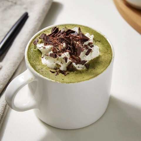 Steaming Matcha Hot Cocoa Protein Mug boasts a vibrant green hue, ideal for a quick, healthy breakfast.