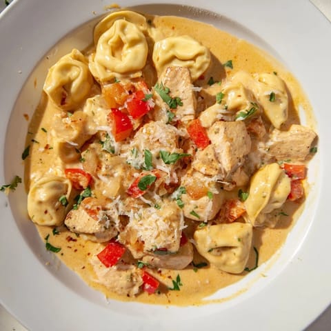 Creamy Zesty Cajun Garlic Parmesan Chicken Tortellini topped with vibrant red peppers and garlic.  