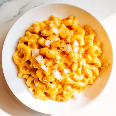 A close-up of golden One-Pot Butternut Squash Mac & Cheese, garnished with fresh herbs.