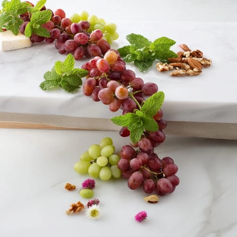 Juicy red and green grapes cascade over a wooden board, ready to be enjoyed as a refreshing snack.