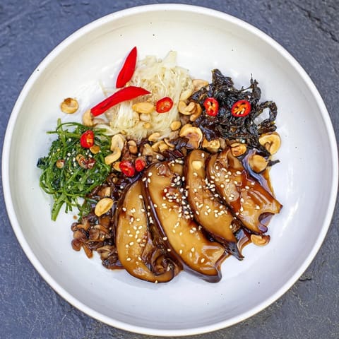 A close-up of the flavorful Umami Bomb Asian Delight arranged with roasted mushrooms and fresh herbs.