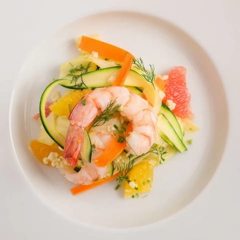 Sizzling presentation of The Coral Reef: tender shrimp and citrus arranged for visual coral effect.