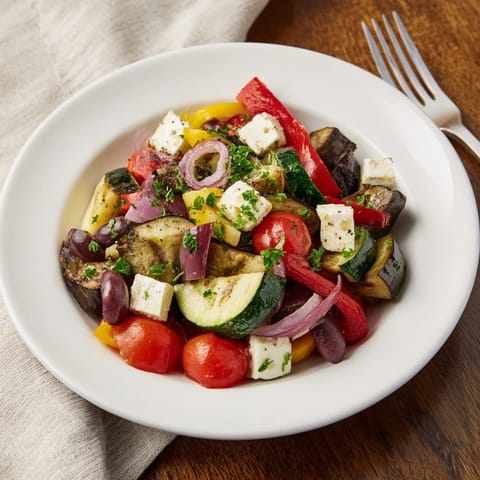 Warm roasted Greek salad on a platter, topped with creamy feta, fresh parsley, and vibrant cucumber.