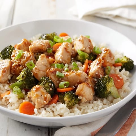 Steam rises from the savory One Pan Honey Garlic Chicken Broccoli Rice, featuring bright green broccoli and perfectly separated grains of white rice.
