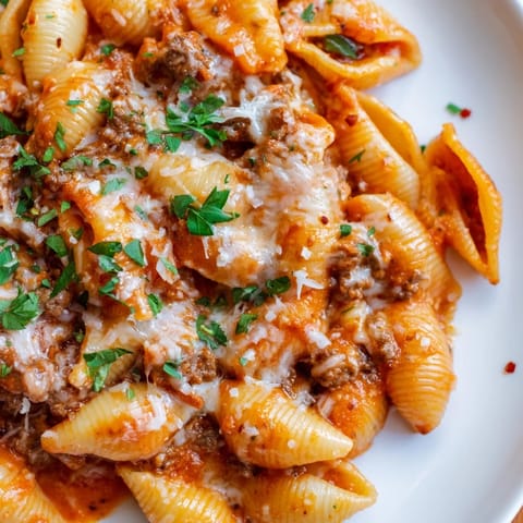 Creamy beef and shells pasta with tender ground beef, pasta shells, and rich tomato cream sauce in a skillet, garnished with parsley.