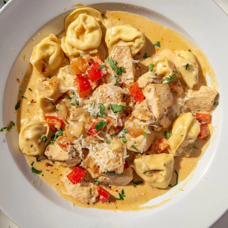 Creamy Zesty Cajun Garlic Parmesan Chicken Tortellini topped with vibrant red peppers and garlic.  