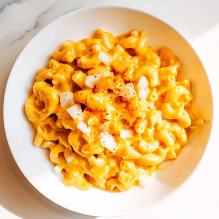 A close-up of golden One-Pot Butternut Squash Mac & Cheese, garnished with fresh herbs.