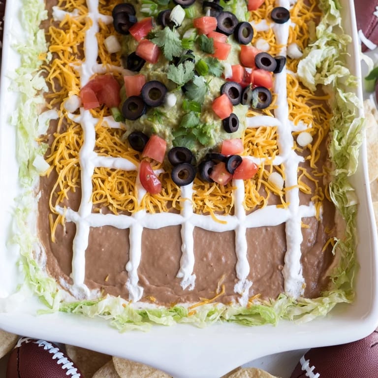 Savory Football Field Dip: A festive layered dip speckled with olives and tomatoes perfect for parties.