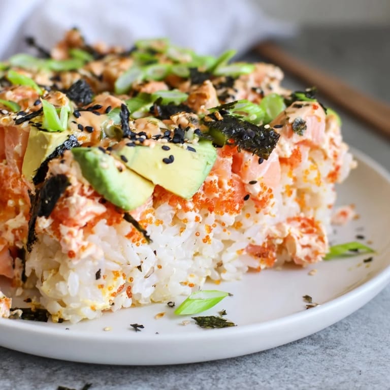 A close-up of a delicious sushi bake casserole with flaked salmon and creamy avocado.